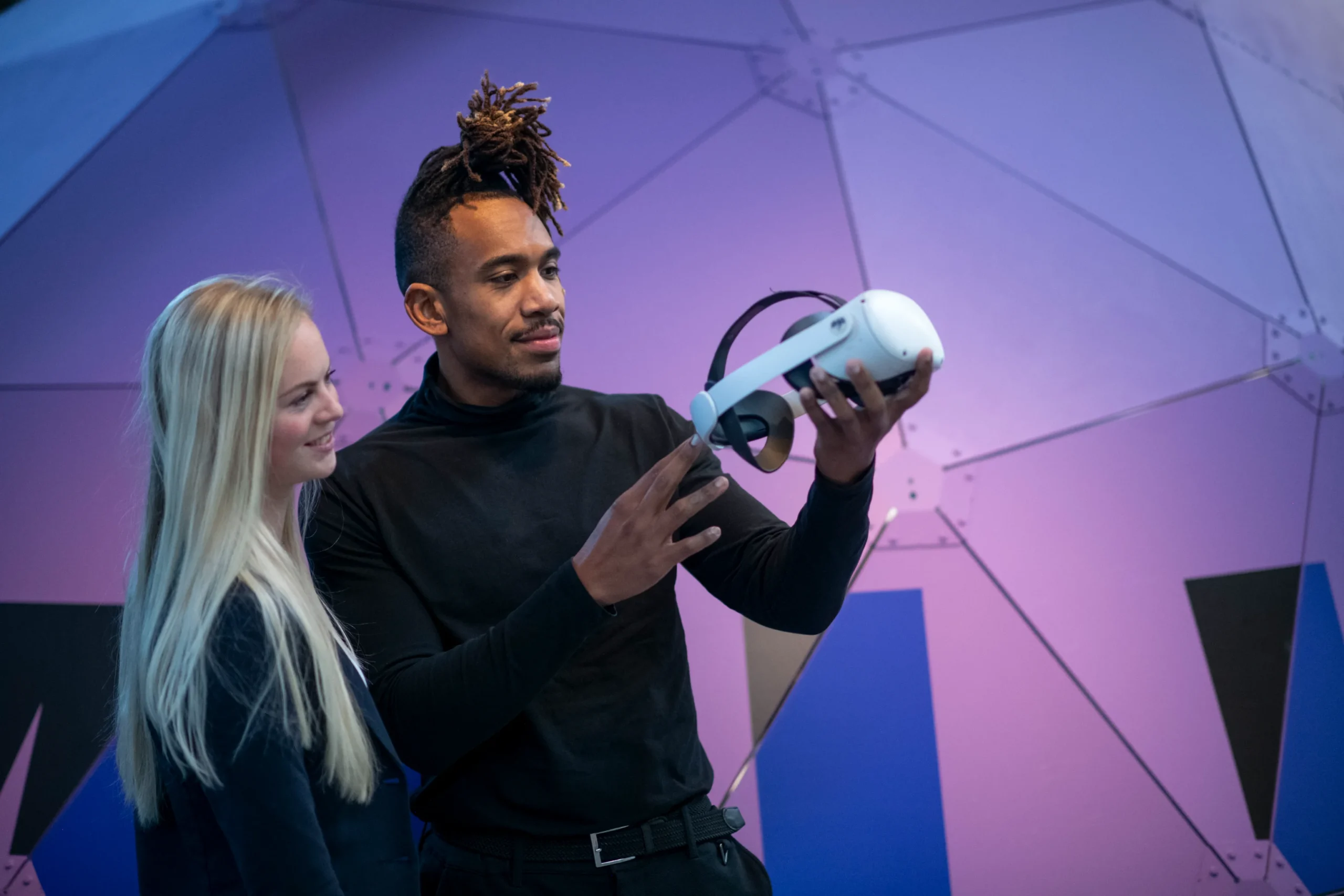 Twee collega's bespreken een virtual reality-headset in een high-tech omgeving.